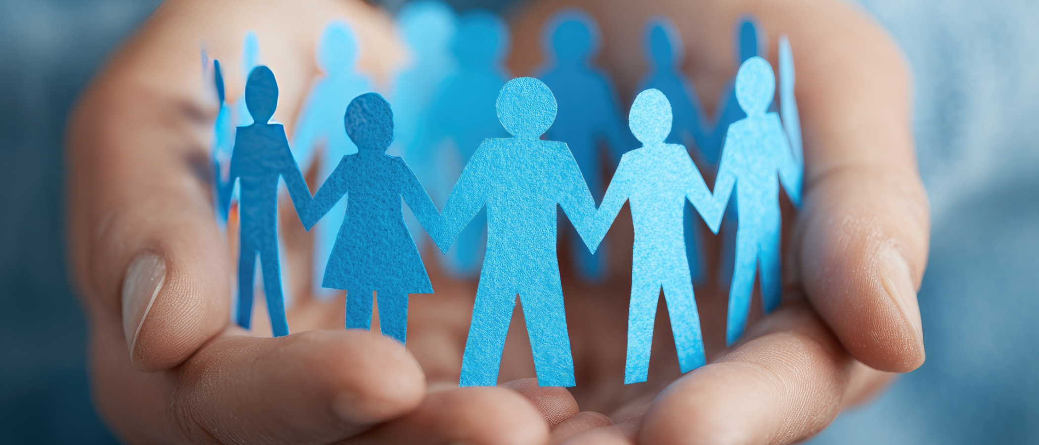 Paper cut-out figures held in cupped hands, symbolising safeguarding, protection, support and community care.