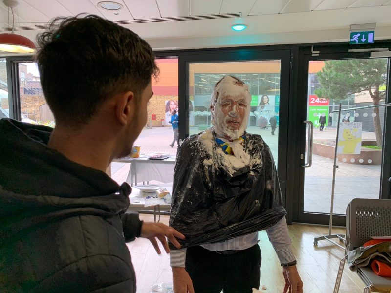 English teacher, John Peacock, gets pied in the face by Barbering students at the Technical Skills Academy