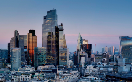 A view of the City of London skyline at dusk, featuring modern skyscrapers including the Walkie Talkie building, surrounded by office towers and historic architecture.